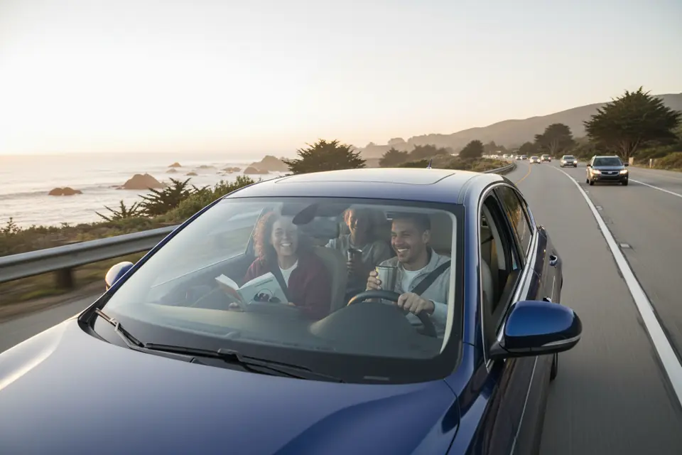 A car commuting along a coastal road in morning light
